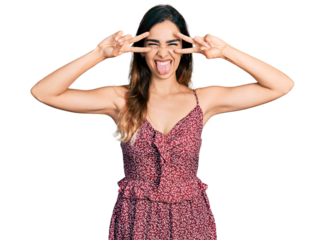 Beautiful hispanic woman wearing bohemian and hippie style doing peace symbol sticking tongue out happy with funny expression.