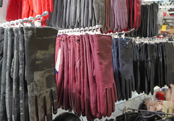 Leather gloves hang in a store, red, black, khaki, for sale to customers. For wearing in winter.