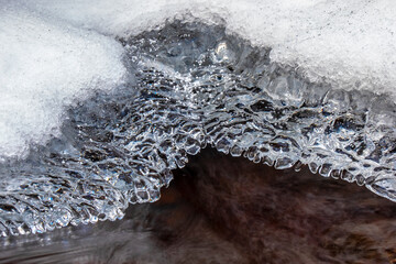 Beautiful icicle formations during the freezing of the stream in winter