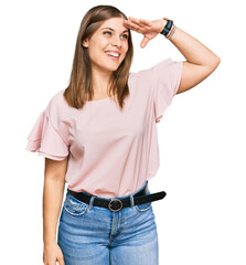 Beautiful caucasian woman wearing casual clothes very happy and smiling looking far away with hand...