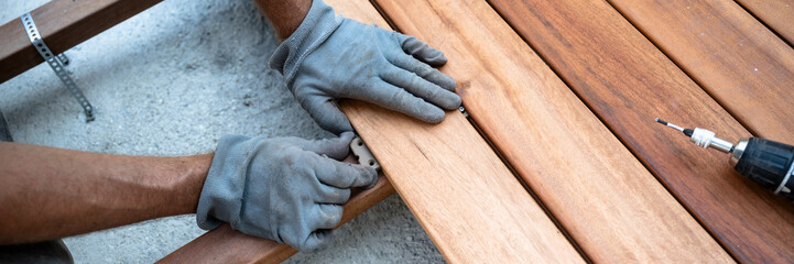 Male hands in protective working gloves placing a plastic spacer bewteen wooden planks