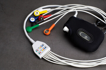 Holter, a compact medical device for a heart rate measurement with all the colorful cables on industrial gray background	