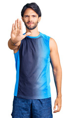 Handsome hispanic man wearing sportswear doing stop sing with palm of the hand. warning expression with negative and serious gesture on the face.