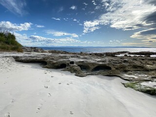 Rocky coast of the ocean. Landscape of a bay with unclear sky. Hummocky natural stones at the shore on the beach.