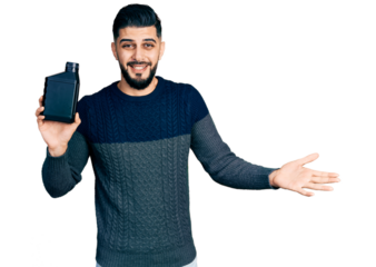 Young arab man with beard holding motor oil bottle celebrating achievement with happy smile and winner expression with raised hand