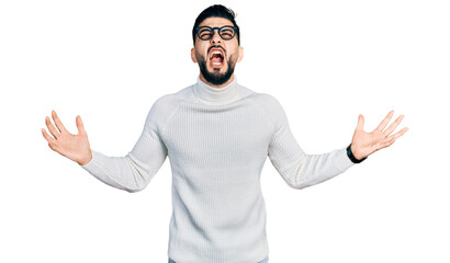 Fototapeta premium Young arab man with beard wearing elegant turtleneck sweater and glasses crazy and mad shouting and yelling with aggressive expression and arms raised. frustration concept.