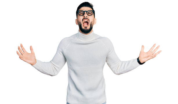 Young arab man with beard wearing elegant turtleneck sweater and glasses crazy and mad shouting and yelling with aggressive expression and arms raised. frustration concept.