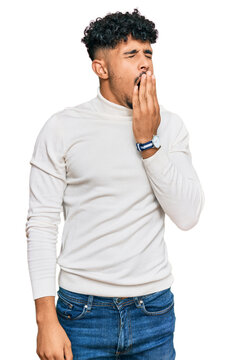 Young arab man wearing casual winter sweater bored yawning tired covering mouth with hand. restless and sleepiness.