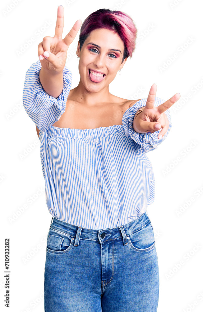 Poster young beautiful woman with pink hair wearing casual clothes smiling with tongue out showing fingers 