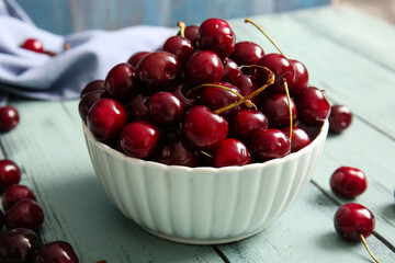 Bowl with sweet cherries on blue wooden table