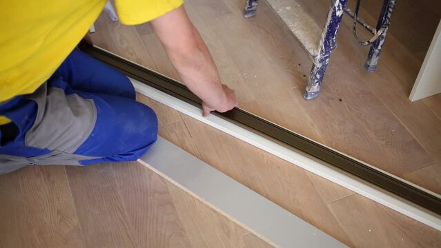 worker attaches guide profile to lower part of sliding wardrobe.