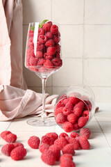 Glasses with fresh raspberries on white tile background