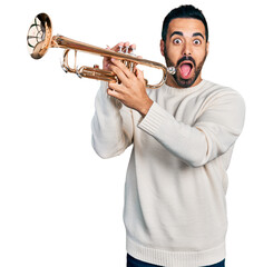 Young hispanic man with beard playing trumpet celebrating crazy and amazed for success with open eyes screaming excited. © Krakenimages.com