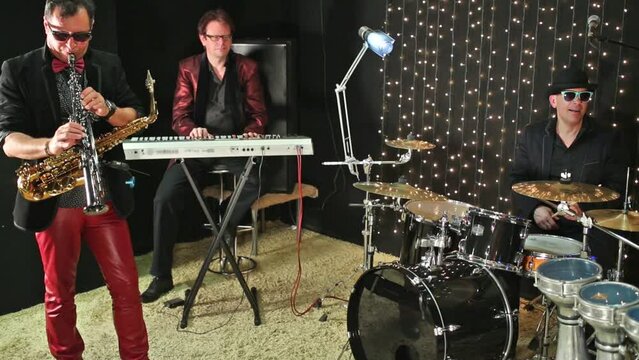 Three men are playing in the studio with a garlands.
