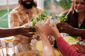 Toast from a group of unrecognizable friends at a celebratory meal. Concept: fun, together