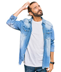Attractive man with long hair and beard wearing casual denim jacket confuse and wondering about...