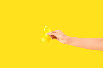Fototapeta premium Woman with yellow awareness ribbon on color background, closeup