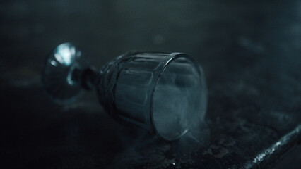 White smoke flies out of a glass goblet lying on the concrete floor