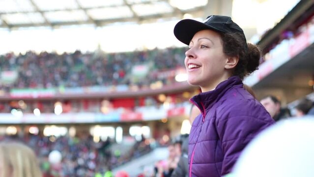 Woman in black cap shouts with red pompoms during football match