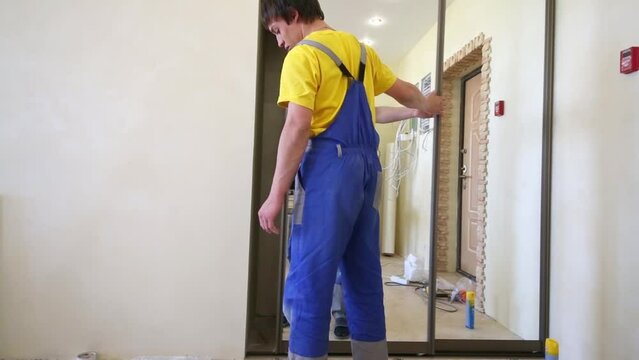 worker examines quality of mounting sliding wardrobe mirrored door