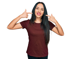 Young hispanic girl wearing casual t shirt smiling cheerful showing and pointing with fingers teeth and mouth. dental health concept.