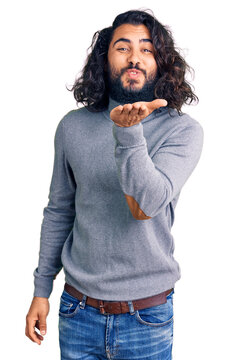 Young arab man wearing casual clothes looking at the camera blowing a kiss with hand on air being lovely and sexy. love expression.