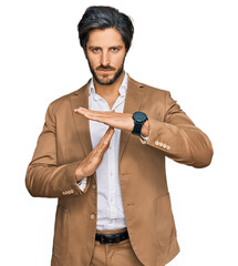 Young hispanic man wearing business clothes doing time out gesture with hands, frustrated and...