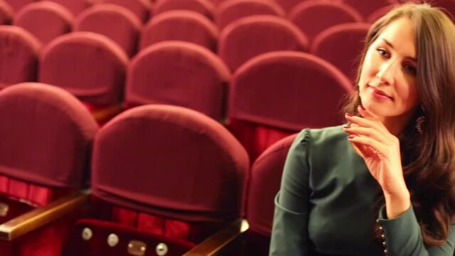 Portrait of pretty woman sitting in empty auditorium in theatre