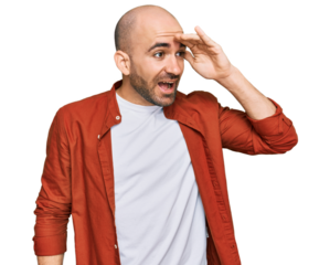 Young hispanic man wearing casual clothes very happy and smiling looking far away with hand over head. searching concept.