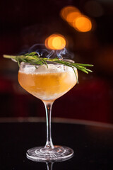 Captivating image of a deluxe cocktail, adorned with ice and burnt rosemary, set against a festive and romantically lit backdrop. Ideal for holiday-themed projects