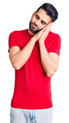 Young handsome man with beard wearing casual t-shirt sleeping tired dreaming and posing with hands together while smiling with closed eyes.