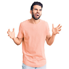 Young handsome man with beard wearing casual t-shirt crazy and mad shouting and yelling with...
