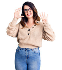 Beautiful young brunette woman wearing casual clothes and glasses showing and pointing up with fingers number nine while smiling confident and happy.