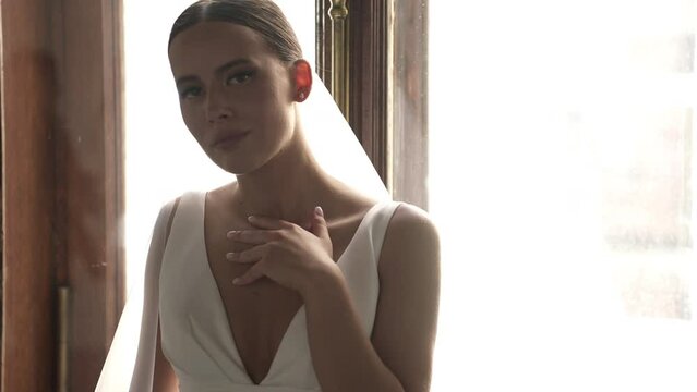 The bride sits by the window and poses for the camera