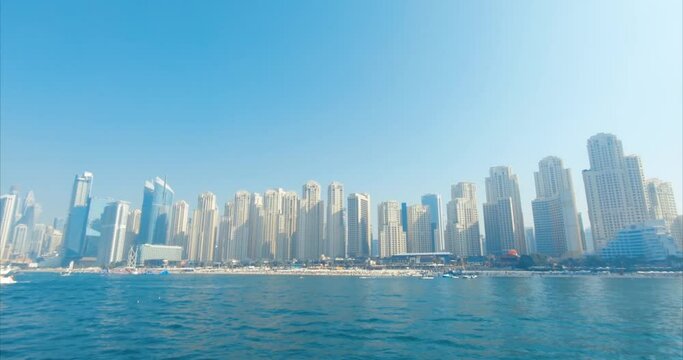 A bright morning in Duba, UAE, JBR: from the boat, the view of the majestic skyscrapers along the shore. A jet ski deftly cuts through the waves of the Persian Gulf, adding to the momentum.