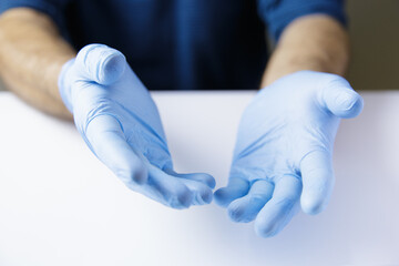 Expressive together hands of doctor or nurse wearing latex gloves on white office table. Place object.