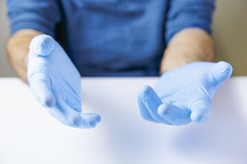 Expressive separate hands of doctor or nurse wearing latex gloves on white office table.