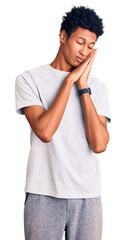 Young african american man wearing casual clothes sleeping tired dreaming and posing with hands together while smiling with closed eyes.