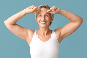 Mature woman doing face building exercise on blue background