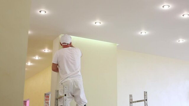 Worker is standing on scaffold and fixing the wall 