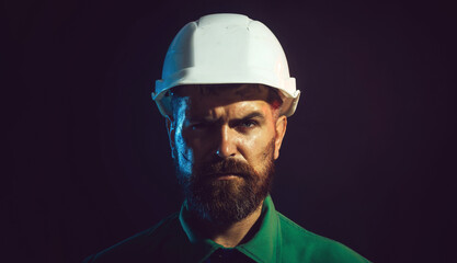Closeup portrait of bearded man in protective helmet. Serious mechanical worker, foreman or repairman in construction hard hat. Male builder, architect or engineer in white hardhat and safety uniform.