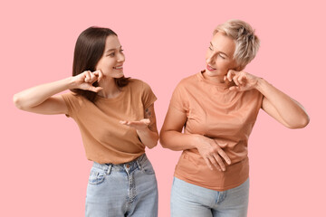 Beautiful women doing face building exercise on pink background