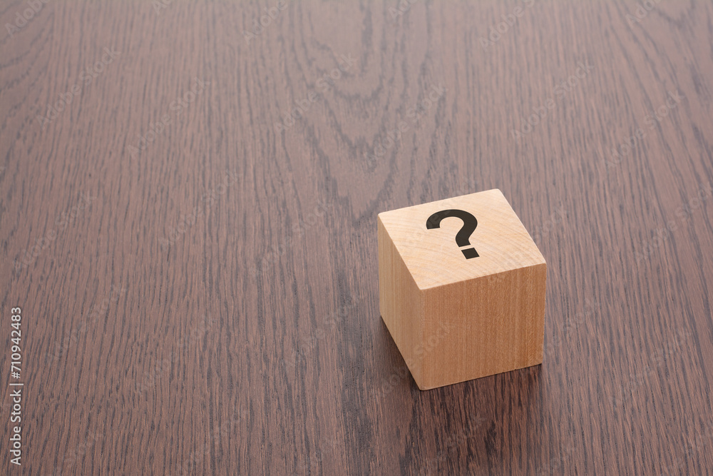 Aufkleber one wooden block with question mark over a brown background with copy space