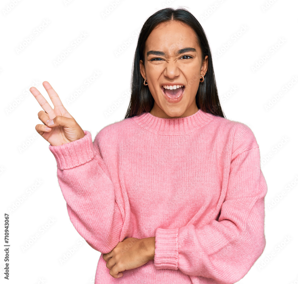 Sticker Young asian woman wearing casual winter sweater smiling with happy face winking at the camera doing victory sign with fingers. number two.