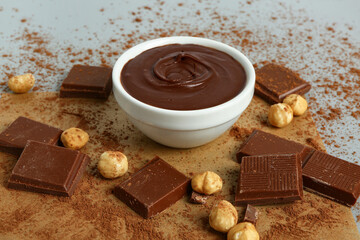 Composition with bowl of tasty melted chocolate and nuts on light background, closeup