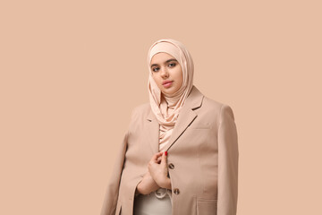 Beautiful young Muslim woman in hijab on beige background