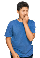 Teenager hispanic boy wearing casual clothes looking stressed and nervous with hands on mouth biting nails. anxiety problem.