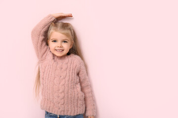 Cute little girl measuring height on pink background
