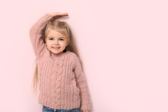 Cute little girl measuring height on pink background