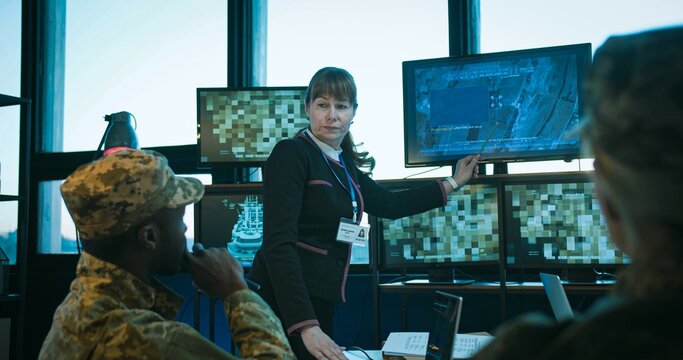 Female head of headquarters holding conference and presentation for military people in uniform. African American man and Caucasian women listening to report od army surveillance.